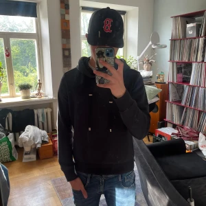 Limitato hoodie - Svart hoodie från Limitato med en stor, färgstark bild på ryggen. Tröjan har huva med snören som är detaljerade med. Perfekt för dig som vill sticka ut med ett unikt tryck och komma ifrån de tråkiga vanliga tröjorna. Bra skick men har små tecken på användning (litet märke på ryggen, se bild 3) 