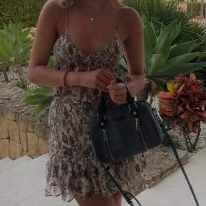 Blommig volangtopp med smala axelband - Söt blus med blommigt mönster i lila, rosa och beige toner. 