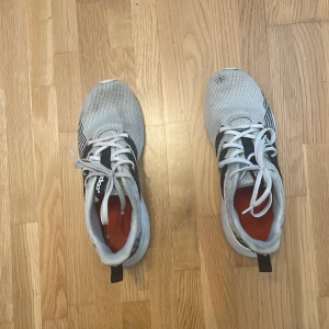 Gråa Adidas sneakers med svarta ränder original price 2679kr - Säljer ett par gråa Adidas sneakers med klassiska svarta ränder på sidorna. Skorna har vit sula, snörning och mesh-liknande ovandel för bra andningsförmåga. Perfekta för vardagsbruk eller lätt träning. Adidas-logga på plösen.