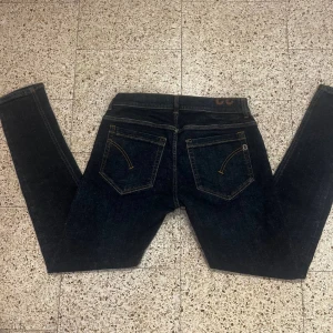 Dondup mörkblå jeansbyxor   - Säljer ett par mörkblå jeansbyxor med snygga kontrastsömmar och klassiska bakfickor. Byxorna har normal passform och raka ben. Perfekta för dig som gillar en tidlös jeansstil.