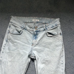 Ljusblå bootcut jeans från Pull&Bear - Säljer ett par ljusblå bootcut jeans från Pull&Bear. Jeansen har klassisk femficksdesign, hög midja och stängs med dubbla silverfärgade knappar. Materialet är denim i bomull och passformen är normal med utsvängda ben. Bra skick. Storlek 44, passar 42 också. 