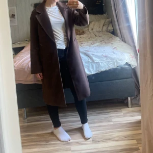 Brun kappa med klassisk krage - Säljer en stilren brun kappa från Bershka med klassisk krage och enkel knäppning framtill. Jackan har raka linjer, två fickor och är helfodrad. Perfekt för dig som vill ha en clean och tidlös look under höst och vinter.