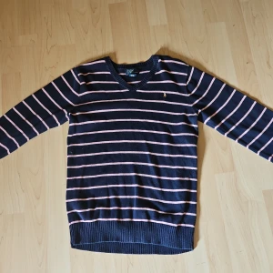 Säljer en jättefin mjuk tröja från polo by ralph lauren - Säljer en jättefin och mjuk tröja från välkända märket Polo by Ralph Lauren i barnstorlek XL (20L). Tröjan är randig i marinblått och rosa, tillverkad i 100 % Pima bomull – vilket gör den extra mjuk och bekväm mot huden.  🧼 Skick: Mycket fint skick, använd sparsamt 🧵 Material: 100 % Pima bomull – hög kvalitet 👕 Färg: Marinblå med rosa ränder 📏 Storlek: XL (20L) – motsvarar ca 14–16 år (men dubbelkolla gärna mått)  Perfekt för både vardag och lite finare tillfällen. Kommer fr