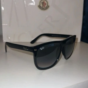 Svarta Ray-Ban Wayfarer solglasögon - Klassiska svarta Ray-Ban Wayfarer solglasögon med bred båge och mörka glas. Snygg och tidlös design med Ray-Ban-logga på skalmen. Tillverkade i Italien och modellen är RB4147. Perfekta för dig som vill ha en cool och ikonisk look. Hela nya