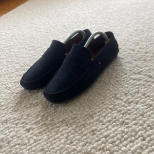 Mörkblå mockaloafers Tommy Hilfiger - Säljer mörkblå mockalofers som aldrig har varit andvända av mig. De är i nyskick och perfekta för somaren. Storlek 41. Tveka inte på att skriva vid funderingar. 