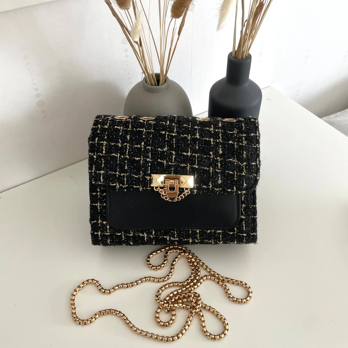 Svart axelväska, med nitar och rutigt tyg.