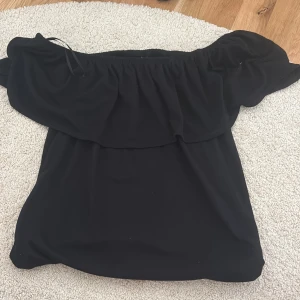 Svart offshoulder topp från Limited - Säljer en svart offshoulder topp från Limited. Toppen har en volangdetalj upptill och är perfekt för dig som gillar en trendig och stilren look. Passar till många olika outfits och är enkel att matcha.