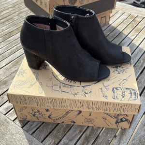 Svarta boots med klack och öppen tå - Säljer ett par svarta boots från sneaky steve med klack och öppen tå. Skorna har dragkedja på sidan och är tillverkade i ett matt material som känns lyxigt. Perfekta för dig som vill ha en stilren men edgy look.