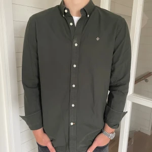 Morris skjorta - Säljer en riktigt mörkgrön morris skjorta i storlek L. Skjortan är i väldigt bra skick utan några defekter. Modellen är 183 cm och väger 82 kg. Skjortan är 75 cm lång och 53 cm lång. Hör av er vid frågor