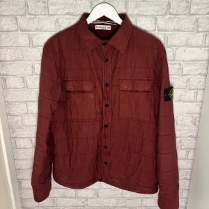 Stone Island jacka - Stone Island overshirt jacka i vinröd färg. Lätt fodrad med tryckknappar och två bröstfickor. Detta är en äldre modell, producerad innan Certilogo/QR-systemet infördes 2014, men 100% äkta. Grymt skick för åldern, inga större skador eller slitningar. Fler bilder i pm, hör av dig vid intress🙌