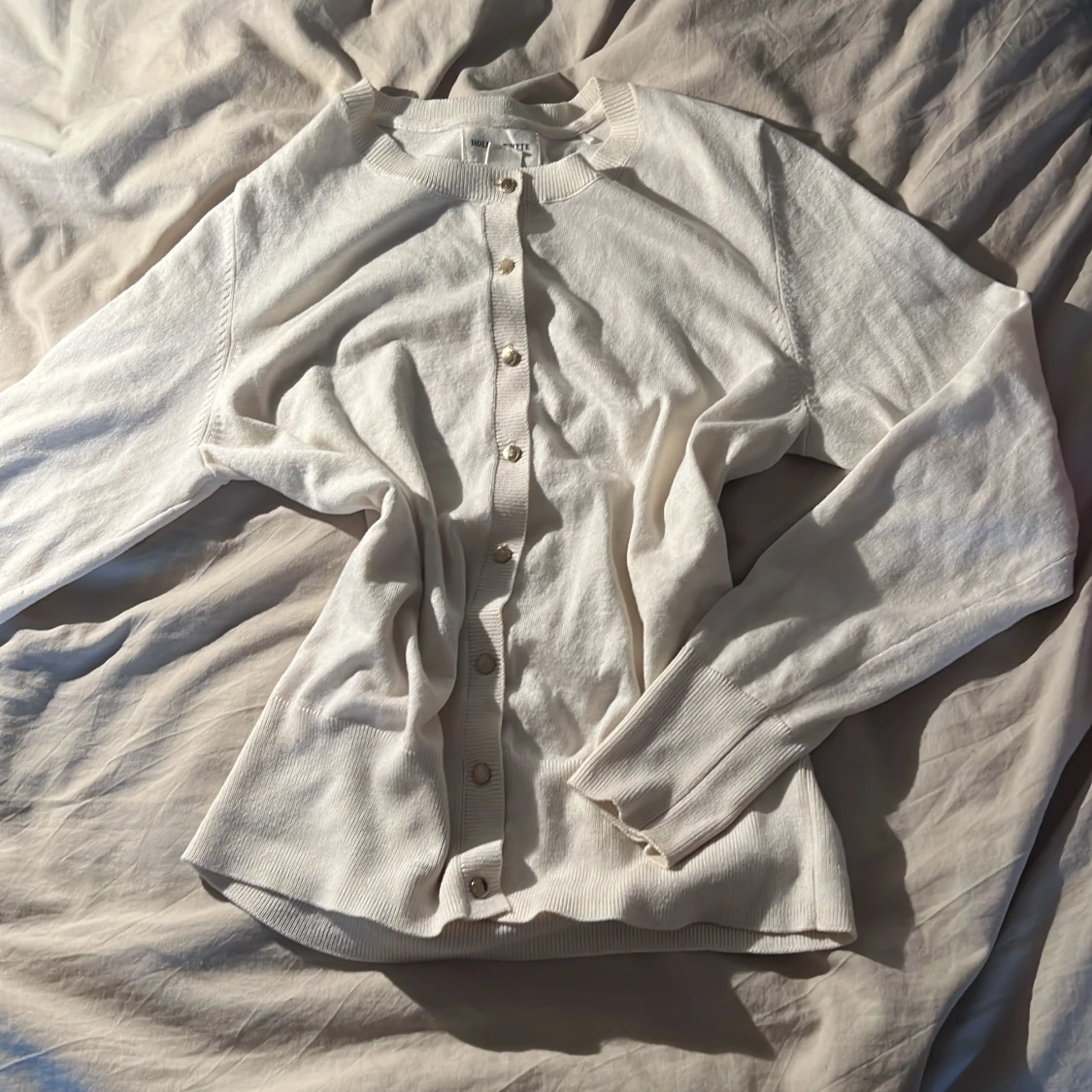 Vit kofta med guldfärgade knappar