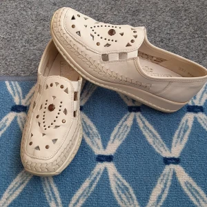 Beige skinnloafers från Rieker - Snygga beige loafers från Rieker i skinn med coola utskurna mönster och dekorativa nitar på ovandelen. Skorna har flätad detalj runt sulan och platt sula för skön komfort. Perfekta för dig som vill ha en unik och luftig sko till vardags. Skor är mycket lätta och bekväma i ny skick. 