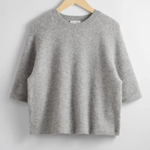 Grå stickad tröja från & Other Stories - Mysig grå stickad tröja från & Other Stories med rund halsringning och rak passform. Perfekt för lager-på-lager och enkel att matcha med olika outfits. Tröjan har långa ärmar och är tillverkad i ett mjukt material.