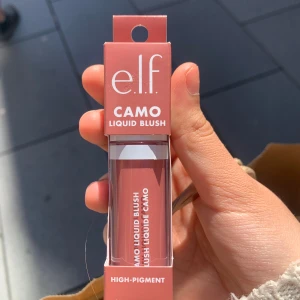 e.l.f. Camo Liquid Blush - Flytande rouge från e.l.f. i en varm, rosabrun nyans. Kommer i en liten genomskinlig tub med applikator och förpackning i matchande färg. Högpigmenterad formula för intensiv färg på kinderna.