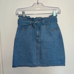 Blå jeanskjol med bälte - En somrig blå denimkjol från Divided By H&M med hög midja och tillhörande bälte med metallspänne. Kjolen har två framfickor och två bakfickor! Perfekt för sommaren! 🩵