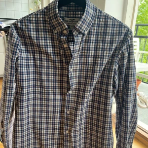 Rutig skjorta från Hampton Republic - Snygg rutig skjorta från Hampton Republic i blått, vitt och inslag av rött och beige. Skjortan har klassisk krage, knappar framtill och lång ärm.