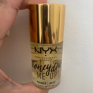 NYX Honey Dew Me Up Primer - NYX Honey Dew Me Up Primer är en genomskinlig ansiktsprimer med guldiga glitterpartiklar. Kommer i en glasflaska och rymmer 22 ml. Perfekt för att ge huden en fräsch och glowig bas innan smink. Öppnad men oanvänd 