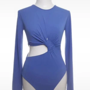 Blå långärmad body med cut-out och twistdetalj - Trendig blå långärmad topp med rund halsringning och snygg cut-out på sidan. Twistdetalj framtill ger en cool look. Prislappen finns kvar💞☺️