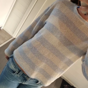 Randig stickad tröja från Zara - Säljer en ljusblå och vit randig stickad tröja från Zara i storlek S. Tröjan har lång ärm och en avslappnad passform, perfekt till jeans. Mjuk och skön med rund halsringning.