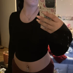 Svart croppad långärmad topp från SHEIN - Säljer en svart croppad långärmad topp från SHEIN. Toppen har en tight passform och är tillverkad i ett mjukt, stretchigt material. Perfekt att styla med höga byxor eller kjol för en trendig look.