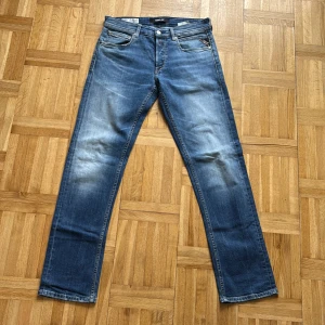 Replay Grover straight fit jeans blå - Snygga Replay Grover jeans i klassisk blå tvätt med raka ben och femficksmodell. Jeansen har subtila slitningar och kontrastsömmar, samt Replay-logga på fickan. Tillverkade i mjukt denim för en skön passform.