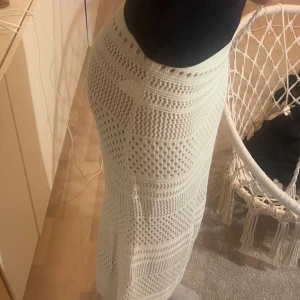 Vit stickad långkjol - Snygg vit stickad långkjol med ett detaljerat mönster. Kjolen har en elastisk midja för bekväm passform och är perfekt för en stilren look. Köpt för 400, jag säljer för 200! Aldrig använd men köpt för 1 år sedan!
