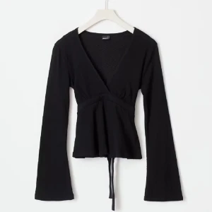 Svart tie topp  - Snygg svart omlottopp med långa ärmar och knytband i midjan. Perfekt för en stilren look. Toppen har en v-ringad design och är tillverkad i ett bekvämt material.