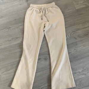 Beige mjukisbyxor med snörning - Säljer ett par bekväma beige mjukisbyxor med elastisk midja och snörning. Perfekta för en avslappnad stil. Byxorna har en rak passform och är tillverkade i ett mjukt material.
