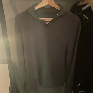 Grå merinoulltröja från These Glory Days - Säljer en stilren grå tröja i superior merinoull från These Glory Days. Tröjan har en dragkedja vid halsen och långa ärmar. Nypris ligger på 1099 o den är använd endast 1 gång. 
