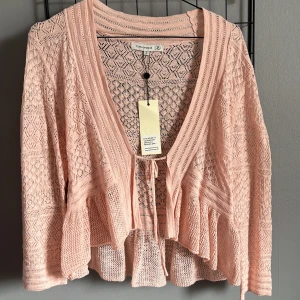 Rosa stickad kofta från Flash Woman - Säljer en söt rosa stickad kofta från Flash Woman. Koftan har ett vackert spetsmönster och knytband framtill. 💞