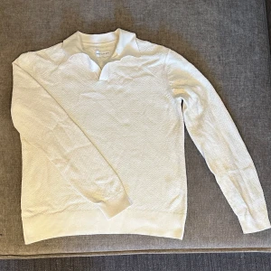 Vit pikétröja från These Glory Days - Säljer en stilren vit pikétröja från These Glory Days. Tröjan har en klassisk krage och långa ärmar med ribbade muddar. Perfekt för en avslappnad men ändå uppklädd look. Använd 1 gång.