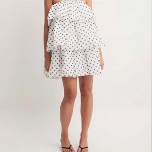 Vit axelbandslös klänning med prickar - En söt vit axelbandslös klänning med svarta prickar med prislapp💓Slutsåld på nakd. Eftersom att den är helt oanvänd och jag enbart säljer då returtiden gått ut kan jag inte tänka mig att sänka pris