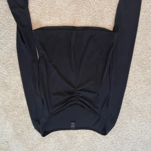 Svart ribbad topp från Romwe - Snygg svart ribbad topp från Romwe med långa ärmar och en smickrande rynkad detalj framtill. Perfekt för en stilren look.