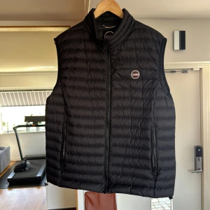 Svart dunväst från Colmar - Säljer en stilren svart dunväst från Colmar. Västen har en dragkedja framtill och en diskret logga på bröstet.