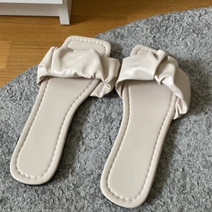 Beige sandaler med volangdetalj - Snygga beige sandaler med en unik volangdetalj över foten. De har en öppen tå och en bekväm passform. Storlek 39 men passar 38🥰jag har 39 men är lite för liten. Jag har aldrig använt dom ute så dom är helt rena och inga skador ❤️från shein 