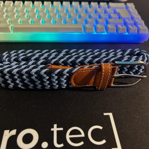 Elastiskt flätbälte i två nyanser av blått - Säljer ett flätat stretchbälte i snygga blå nyanser  ljusblått och marinblått i diagonal väv. Bekvämt och justerbart utan fasta hål. Läderdetaljer och metallspänne i klassisk design. Har även två andra bälten i andra färgen på min profil så hör av dig om det vore av intresse att köpa flera så kan vi göra någon deal.