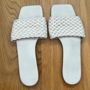 Vita flätade sandaler - Snygga vita sandaler med en bred flätad rem över foten. Perfekta för sommardagar med sin stilrena design och bekväma passform.