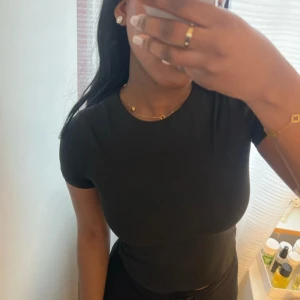 Svart kortärmad topp - Säljer en stilren svart kortärmad topp med en tight passform. 