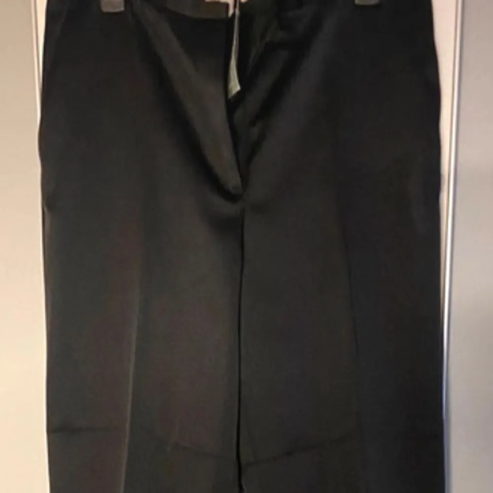 Snygga svarta kostymbyxor från H&M i återvunnen polyester och viskos. Byxorna har en klassisk rak passform och hög midja, perfekt för en stilren look. De har diskreta fickor och en elegant design som passar till många tillfällen.storlek 42.nyskick med lappar . Farkut & Housut.