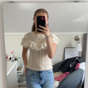 Vit spetsblus med volangdetaljer - Säljer en söt vit spetsblus med vackra volangdetaljer runt axlarna. Blusen har en fin struktur och är perfekt för en romantisk look. Passar bra till både jeans och kjol. Skriv gärna för fler bilder eller andra frågor💗
