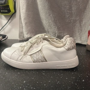 Vita sneakers från Michael Kors - Snygga vita sneakers från Michael Kors med guldiga detaljer. I bra skick! Använda men få gånger!