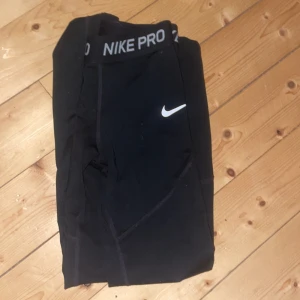 Svarta tights från Nike Pro - (Dom är i st 140/158) Säljer ett par svarta Nike Pro tights med elastisk midja och vit logga. Perfekta för träning med en tight passform som ger bra stöd. Materialet är stretchigt och bekvämt.