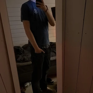 Blå t-shirt från Burberry - Säljer en snygg blå t-shirt från Burberry med ett broderat märke på bröstet. T-shirten är kortärmad och har en klassisk rund halsringning. Perfekt för en stilren look. Jag är 183 och den passar som på bild!