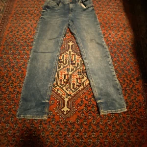Blå jeans från Lindex - Säljer ett par klassiska blå jeans från Lindex. De har en normal passform med raka ben och femficksdesign. Perfekta för en avslappnad stil. SLIM FIT