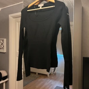 Svart ribbad tröja - Snygg svart ribbad tröja med lång ärm och rund halsringning. Perfekt för kyligare dagar och kan enkelt matchas med olika outfits. En stilren baströja som passar i garderoben.