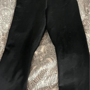 Svarta träningsbyxor från Nike - Säljer ett par svarta träningsbyxor från Nike. Perfekta för träning med en bekväm passform och stilren design. Byxorna har en diskret Nike-logga på benet. Byxorna är av den modellen som har kortare ben.