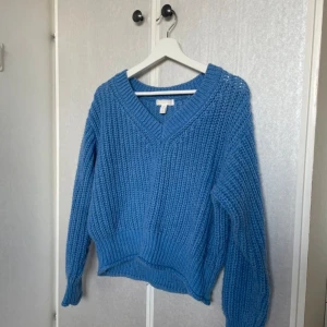 Blå stickad tröja från H&M💓 - Säljer en mysig blå stickad tröja från H&M med v-ringning. Tröjan har en avslappnad passform och långa ärmar, perfekt för kyligare dagar. Den ribbade strukturen ger en extra touch av stil. Perfekt för att hålla sig varm och trendig!