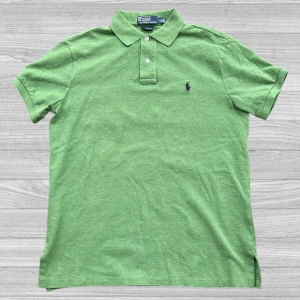 Ralph Lauren piké - Säljer en snygg grön pikétröja från Ralph Lauren med klassisk krage och knappar framtill. Tröjan har en broderad logotyp på bröstet och är perfekt för en stilren look. Passar bra till både jeans och chinos. 🌿