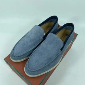 Blå mockaloafers från Loro Piana - Snygga blå loafers i mocka från Loro Piana. Perfekta för en stilren look med en bekväm passform. Skorna har en rund tå och en ljus sula som ger en fin kontrast till den mörkblå färgen. Obs! Skorna är beställda från leverantör, hör av er för mer info eller bilder✅