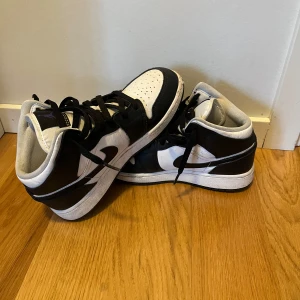 Nike Air Jordans i svart och vit - Säljer ett par Nike Air Jordans i klassisk svart och vit färgkombination. Skorna har snörning och en ikonisk design med perforerade detaljer på tån. Perfekta för sneaker-entusiaster! Priset är inte hugget i sten 